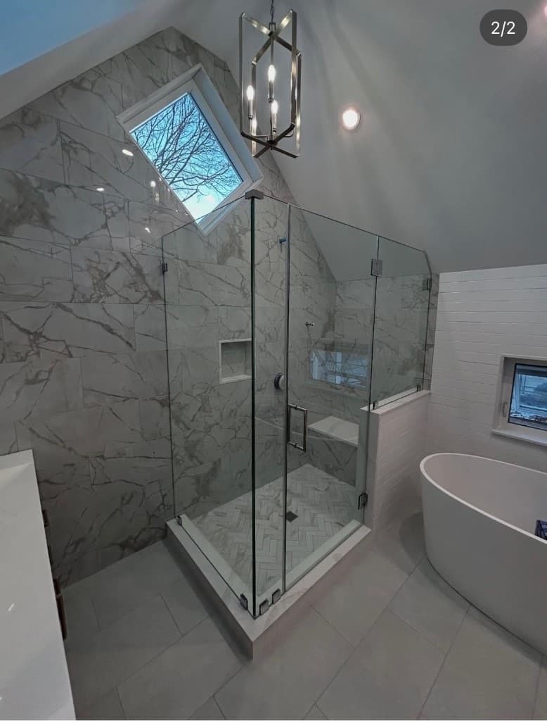 Custom frameless shower enclosure with vaulted ceiling and marble tile